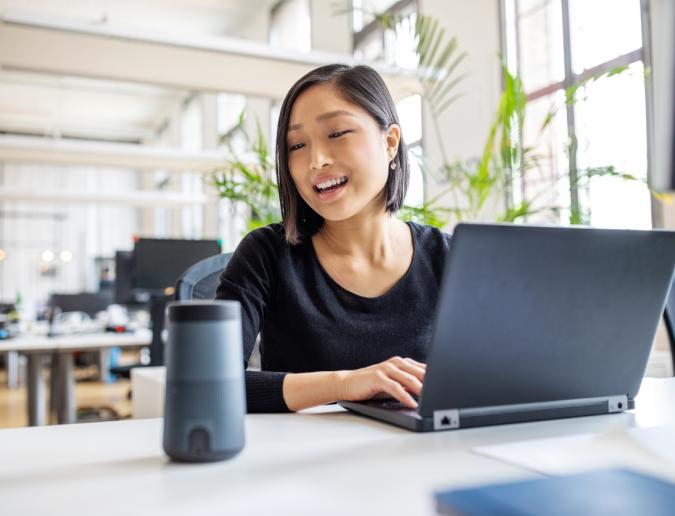 Businesswoman talking to virtual assistant at her desk.