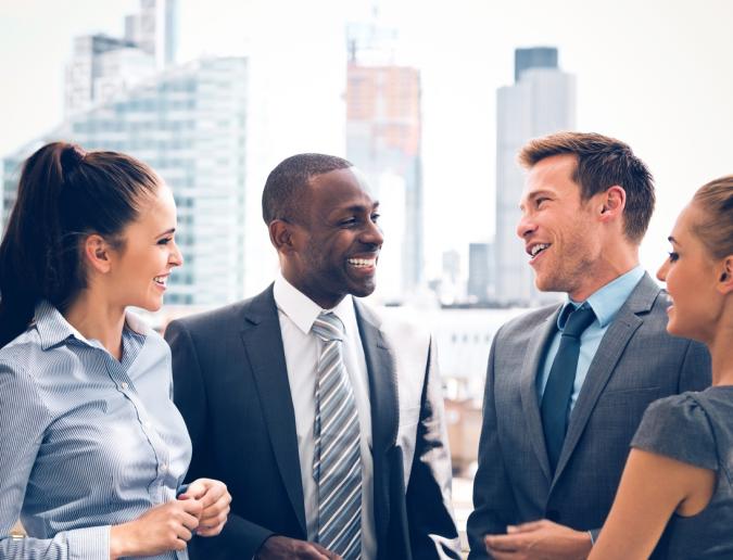 Group of happy business people talking outdoor with city scape in the background.